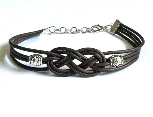 Brown leather Celtic jewelry bracelet with intricate knot design and silver bead accents